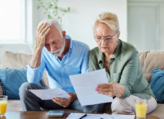 Worried senior couple checking bills and calculating expenses.