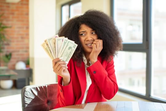 pretty afro black woman holding large handful of cash and feeling scared and worried