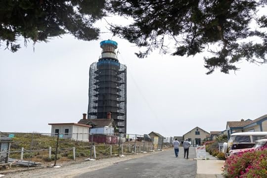 Tourists walk past the Pigeon Point Lighthouse as it undergoes restoration underneath its protective scaffolding, Thursday, Aug. 1, 2024. (Karl Mondon/ Bay Area News Group)