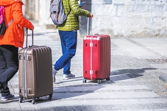 people walking down the street with large suitcases on wheels