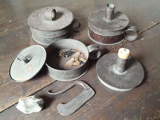 Old fashioned tinder box with flint, striker, and char cloth. The lid doubles as a candle holder.
