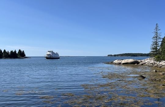 A ferry on blue ocean water with rock outcroppings and pine trees