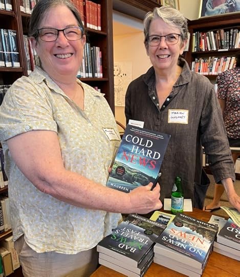 A woman holding a book with the title Cold Hard news while another woman stands next to her