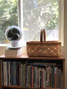 fan and basket on top of a bookshelf
