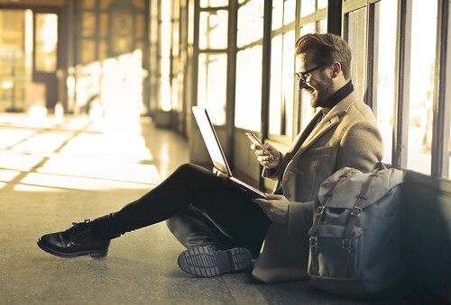 Guy in airport working on his laptop. From Common Mistakes To Avoid When Traveling And Running A Business