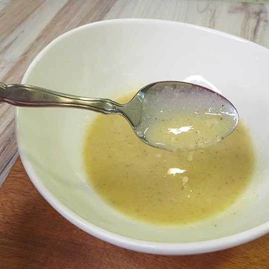 Spoon with caesar dressing with no anchovies on the spoon and in a bowl