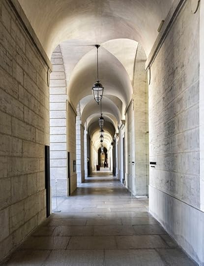 White stone corridor with arched roof and pendant lights handing down, as far as one can see.