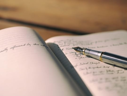 Open notebook with cursive writeing and a silver fountain pen.