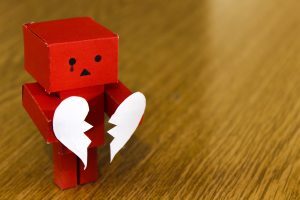 Crying robot holding broken heart