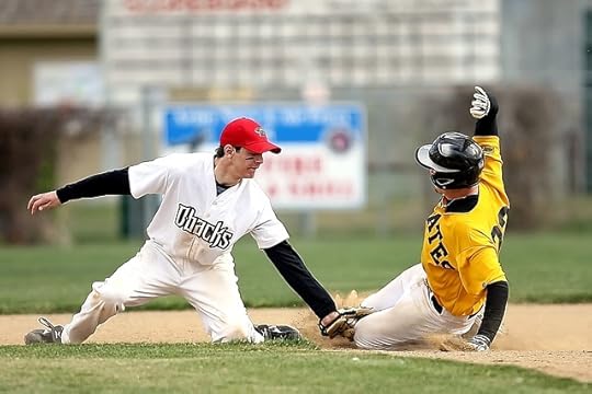 baseball player in yellow, black, and white unfirom sliding into base as a player in black and white uniform tries to stop him.