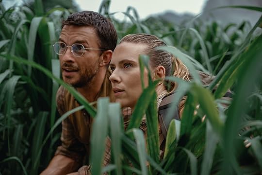 Jonathan Bailey and Scarlett Johansson look through tall grass in Jurassic World Rebirth.