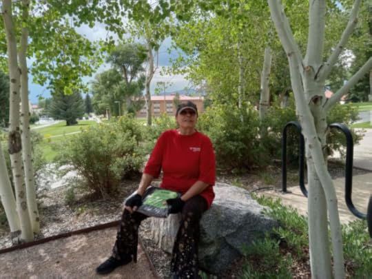 Author Kaye Lynne Booth sitting on a rock in an Aspen grove.