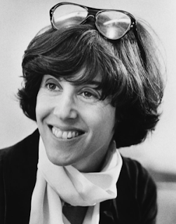 A black and white photo of Nora Ephron. It looks like a professional headshot, she's looking off to the side, with glasses on her head. She's about thirty, and it's possibly the 70s.