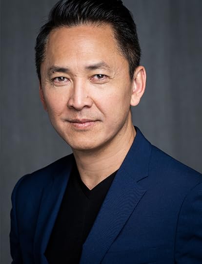 Head and shoulders color portrait of Viet Thanh Nguyen. He is slightly turned to the left and facing the camera with a slight smile.