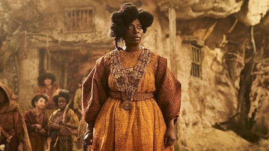 The Gund in an orange dress standing inher village on The Rings of Power
