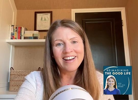 screenshot of Amy Julia recording a podcast. She is sitting in her office with a mic in front of her. She is smiling widely!