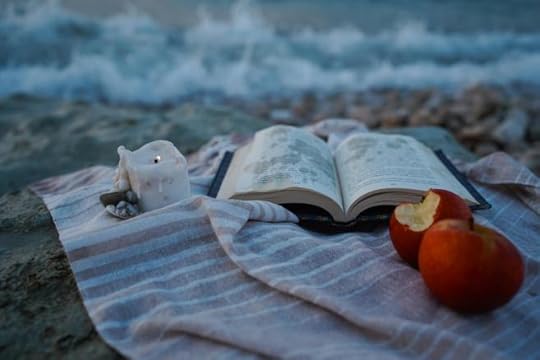 a book and an apple on the beach