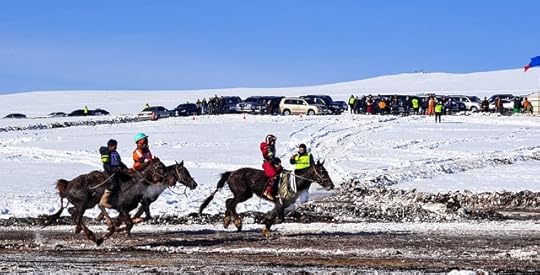 4 horses racing through the snow, with riders and an audience on a nearby hill.