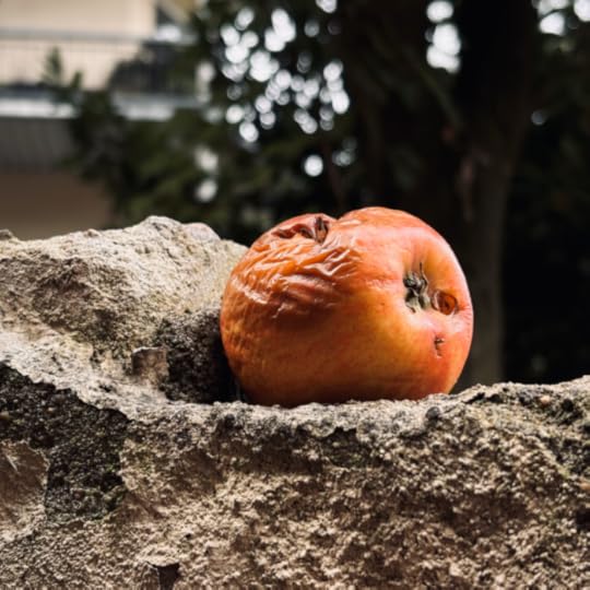 Ein gammelnder Apfel auf einem Mauervorsprung