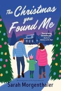 Illustrated cover showing three white people in winter clothes, a man in a blue jacket and pale scarf holding the hand of little girl in a pink unicorn beanie and a green jacket who is in turn holding the hand of a woman wearing a pink jacket and earmuffs. They are walking between two Christmas trees down a path cleared of snow, toward a two story wooden cabin/house.