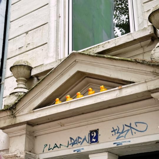 Vier Quietscheentchen über einer Haustür in Ottensen, in einem giebeligen Dekoelement der Fassade abgestellt