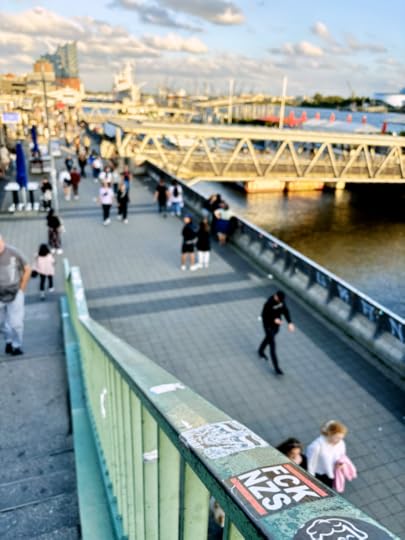 Die Promenade an den Landungsbrücken, von der Treppe aus aufgenommen, die zur S-Bahn-Station führt. Auf dem Treppengeländer ein Aufkleber 