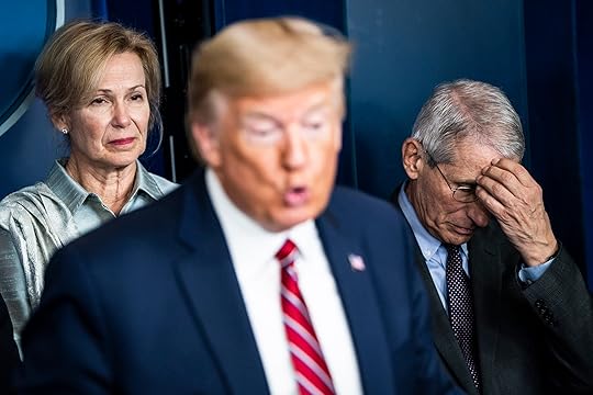 Donald Trump out of focus in the foreground with Dr. Deborah Birx behind him to the left and Dr. Anthony Fauci to his right, with his head in his hand.