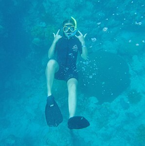 Teen at the great barrier reef holding up a shaka OK