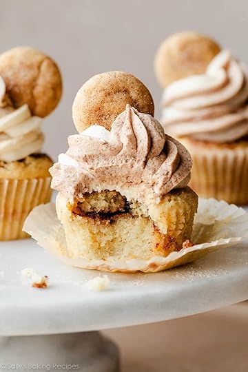 snickerdoodle cinnamon-swirled cupcake with bite taken out on marble cake stand.