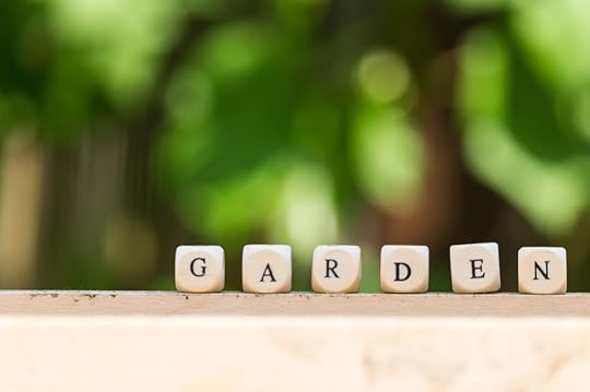 the word garden, put together from single wooden letters in front of a wine plant in the background of the garden at summer time. gardening season has begun