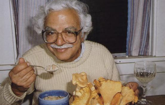 A smiling man eating mushroom soup. 