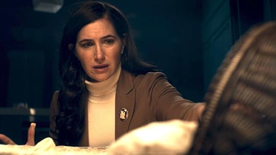 Agatha Harkness dressed like the head of the PTO no one likes sheds a tear while kneeling to look at a bassinet on Agatha All Along