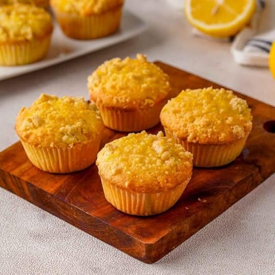 Four Lemon Drizzle Muffins on a wooden platter.