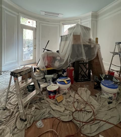 ladders, paint tins, paint trays and rollers on a dust sheet in the middle of an otherwise empty room