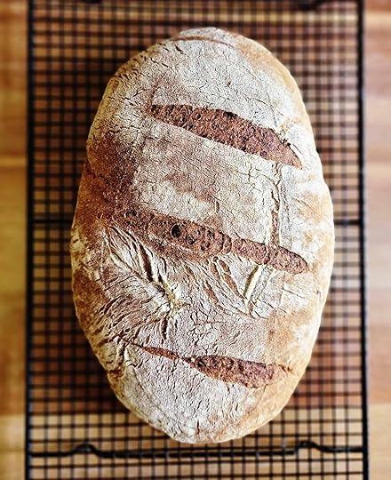 A loaf of rye sourdough cooling on a rack.