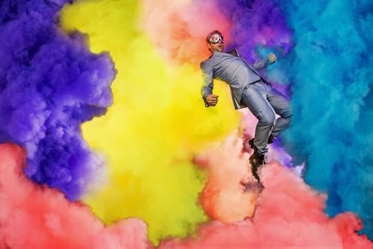 An experimental photography art piece of Chase Jarvis in a shiny silver suit, wearing Goggles, and appearing to float amongst clouds of rich purple, yellow, red, and cyan smoke.