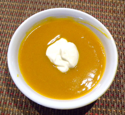 white bowl of butternut squash soup with a dollop of sour cream in the middle
