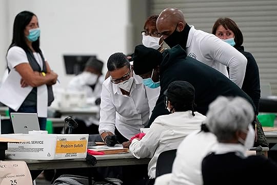 FILE – Election officials huddle around a table as absentee...