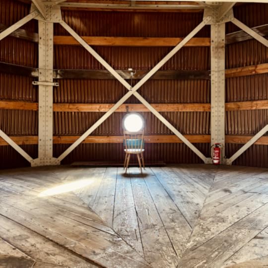 Ein leerer Stuhl vor einem kleinen, runden Aussichtsfenster im Turm von St. Petri