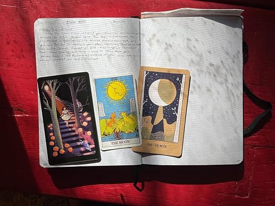 Three Moon cards laid out on a journal lit by moonlight filtered through the trees.