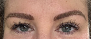 A close up of my eyes. They're blue, and I have long (fake) black eye lashes. My eyebrows are clearly defined, bold, dark brown, with individual (fake) hairs visible.