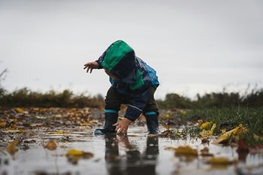 Cute little child playing in a puddle during rain. Why is it so hard to be in the present? 