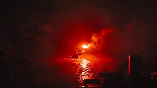 Batman carries a flare through a flooded arena in The Batman