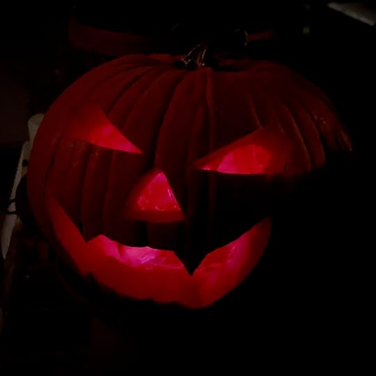 a slightly wicked looking jack'o'lantern grins at the camera. the light inside it is hot pink.