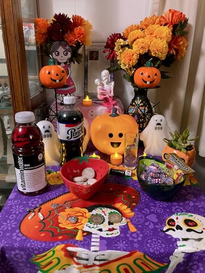 A Day of the Dead "ofrenda" or offering. It's a small table, with a vibrant Mexican mantle, covered with food and items the deceased enjoyed in their life. There's marigolds, little candles, and a remembrance plaque, among others.