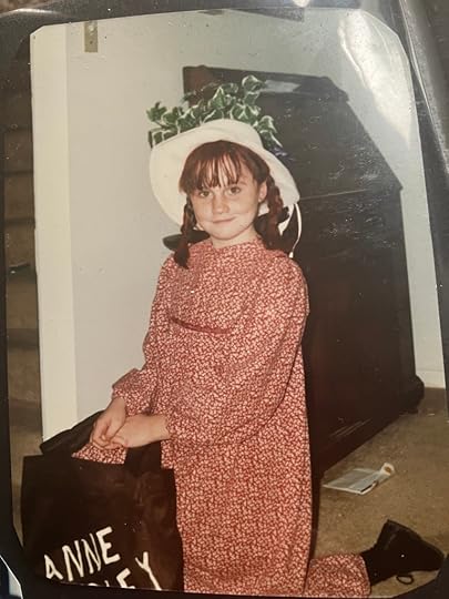 Kerry as a young girl, with red braids, a white hat, and a long red dress