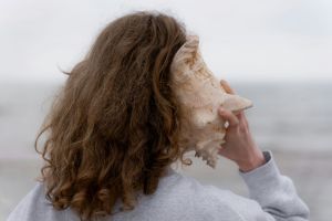 Woman with a sea shell to her ear