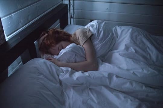 Darkened room witha women curled up in a white duvet
