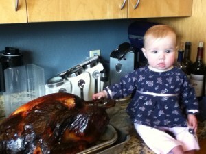 Toddler holding on to a cooked turkey