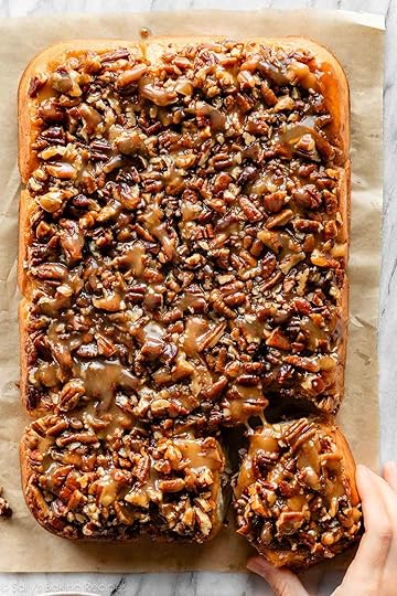 hand pulling a maple pecan sticky bun away from the batch.
